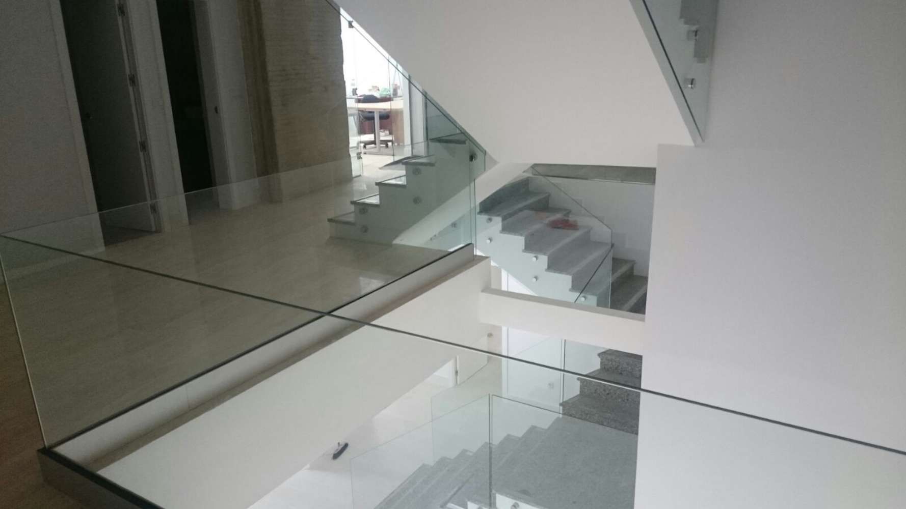 Una escalera con barandilla de cristal en una casa.