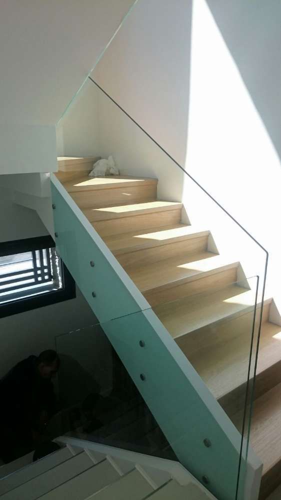 Una escalera de madera con barandilla de cristal en una casa.