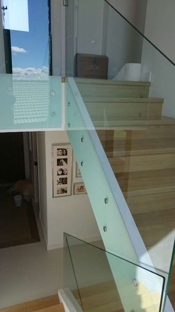 Una escalera con barandilla de cristal y escalones de madera.