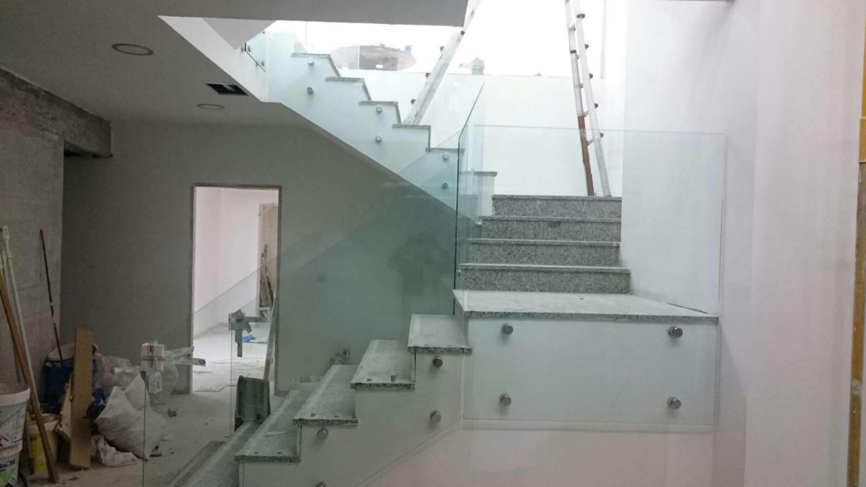 Se está construyendo una escalera con barandilla de cristal en una casa.