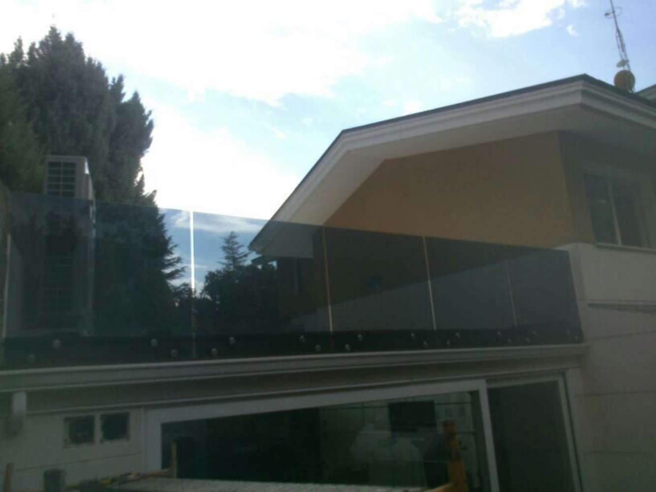 Una casa con balcón y árboles al fondo.