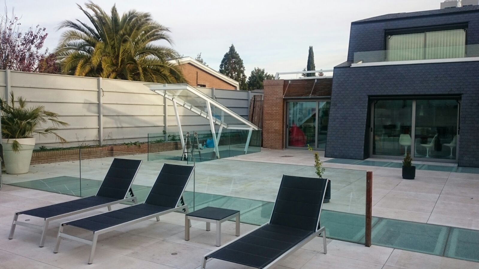 Dos sillones negros están sentados frente a una piscina.