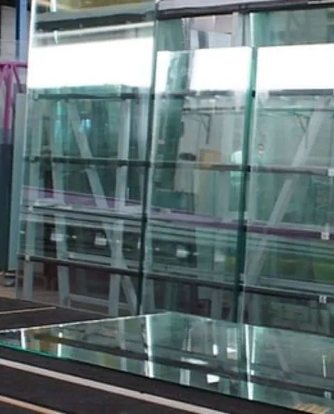 Una mesa de cristal está situada delante de una pared de estantes de cristal.