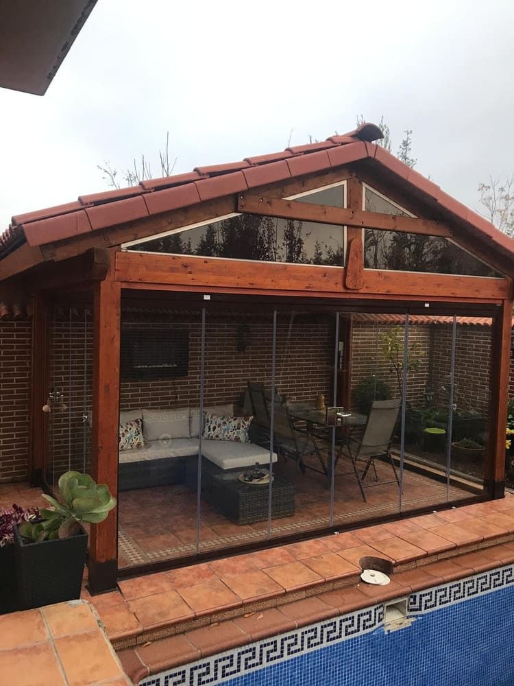 Un cenador de madera con puertas corredizas de vidrio sobre una piscina.