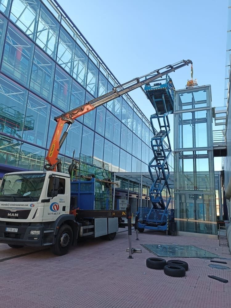 Un camión con una grúa acoplada está estacionado delante de un edificio.