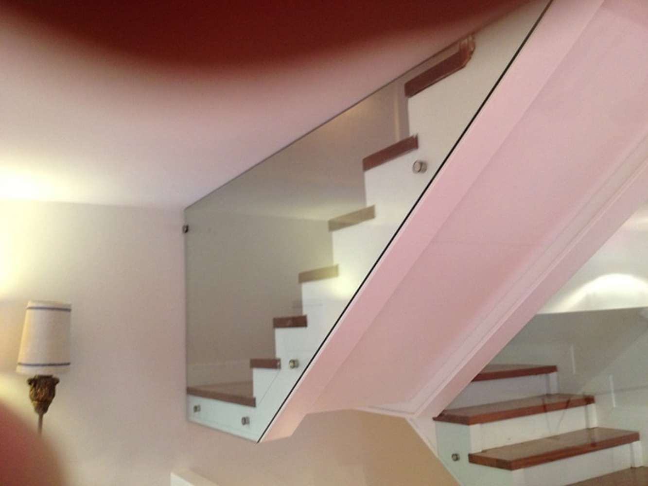 Una escalera con barandilla de cristal y escalones de madera.