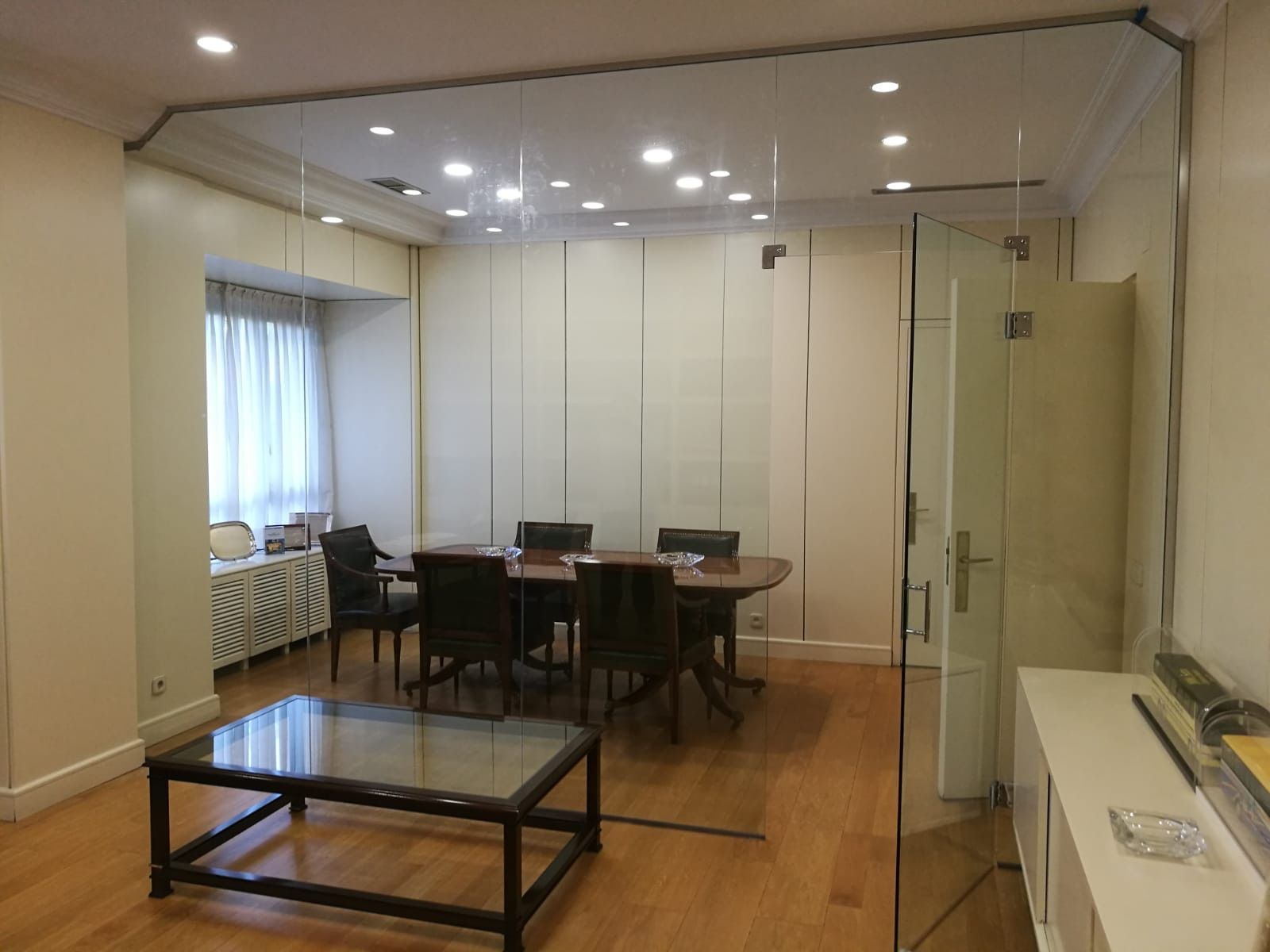 Una habitación con una pared de cristal y una mesa y sillas.