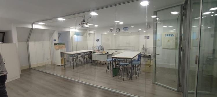 Una habitación con mesas y sillas y una pared de cristal.