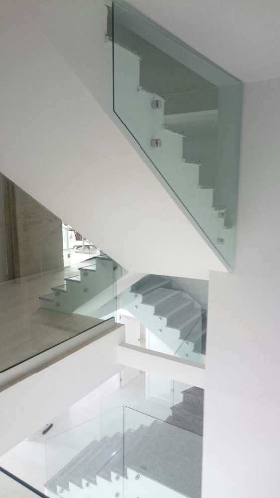 Una escalera moderna con barandilla de cristal en una casa.