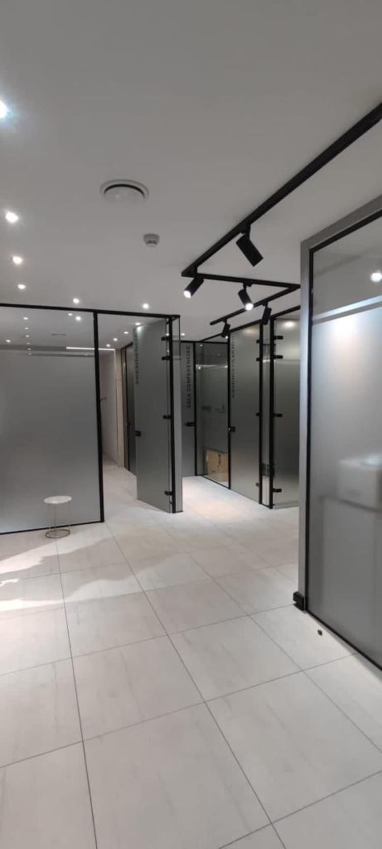 Un pasillo con muchas paredes y puertas de cristal.