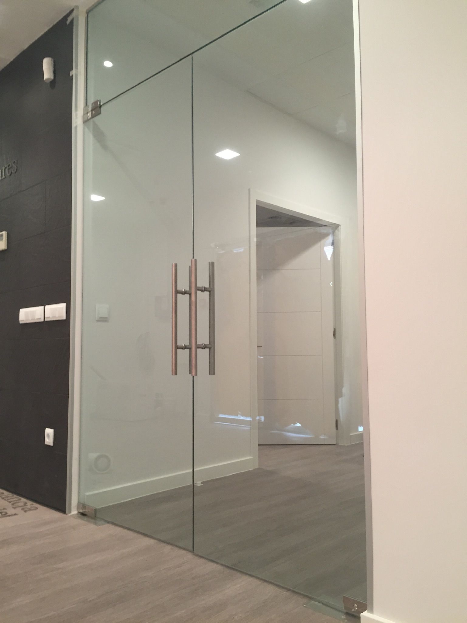 Un pasillo con puertas corredizas de vidrio y una pared negra.