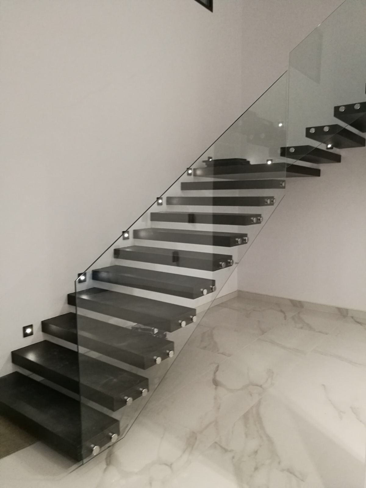 Una escalera con barandilla de cristal en una habitación.