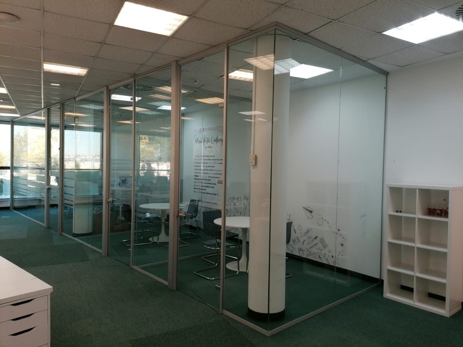 Una habitación con una mesa y sillas y una pared de cristal.