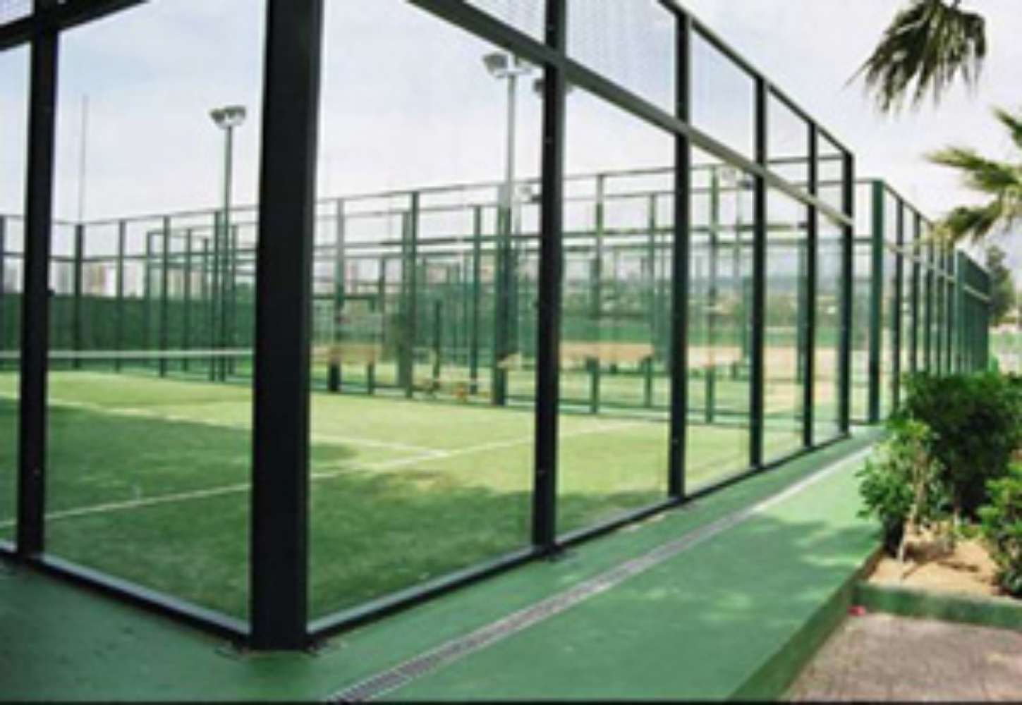 Una cancha de tenis está detrás de una valla de vidrio