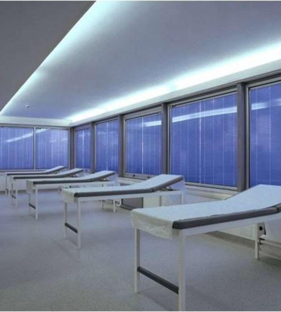Una fila de sillones blancos en una habitación con persianas azules.