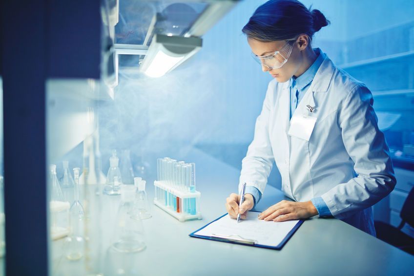 Una científica está escribiendo en un portapapeles en un laboratorio.