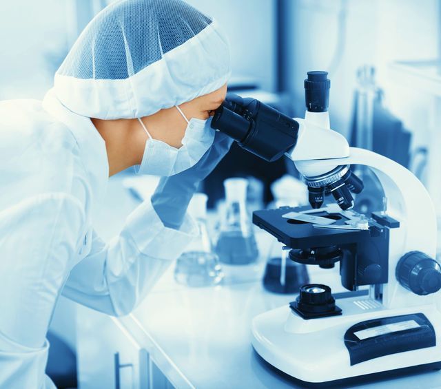 Un científico mirando a través de un microscopio en un laboratorio.