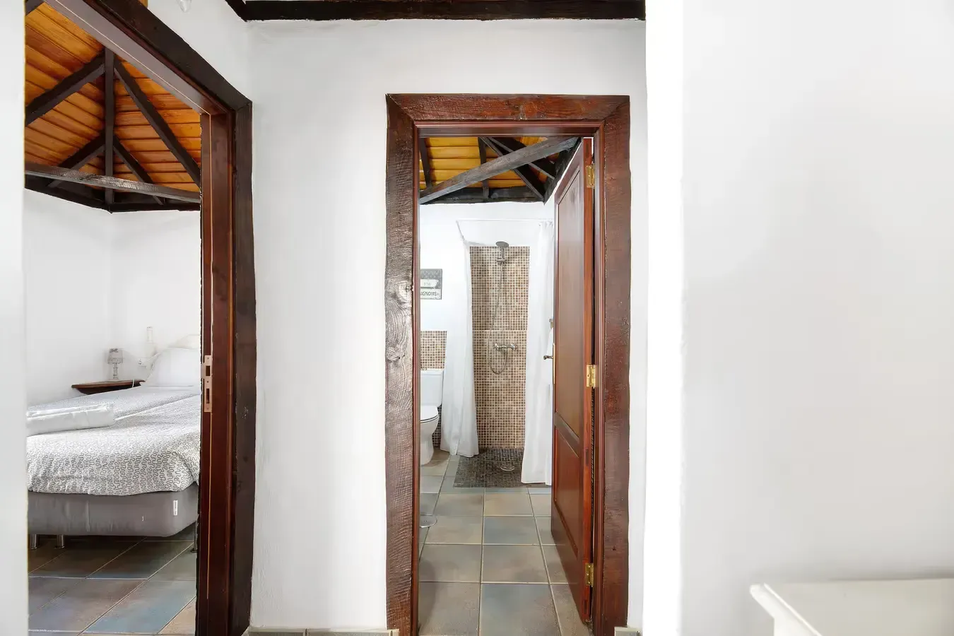 Pasillo con puertas a los dormitorios, uno con cama y otro con alfombra estampada.