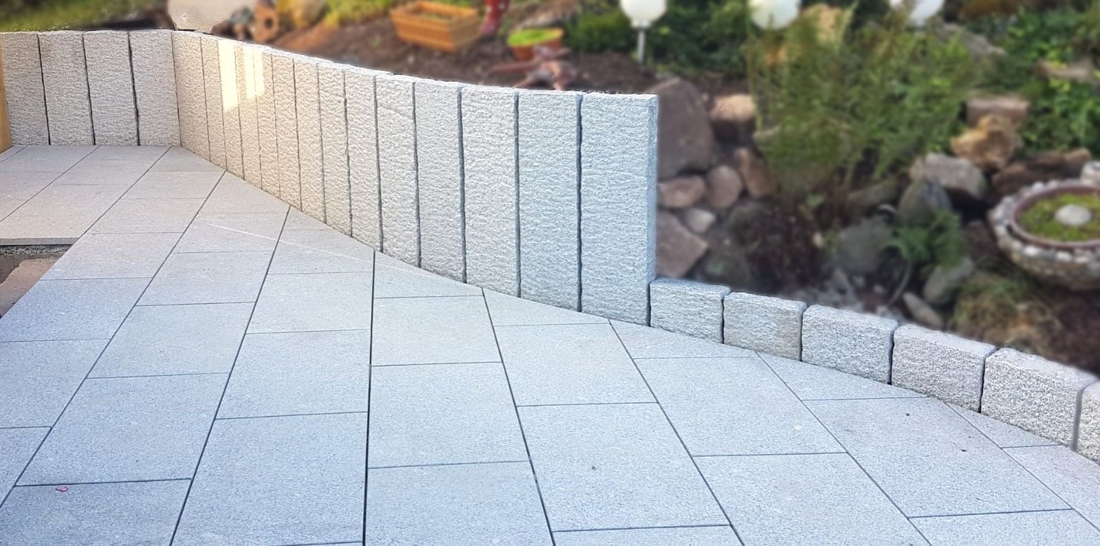 Hellgraue Pflastersteine mit farblich passender Beeteinfassung.