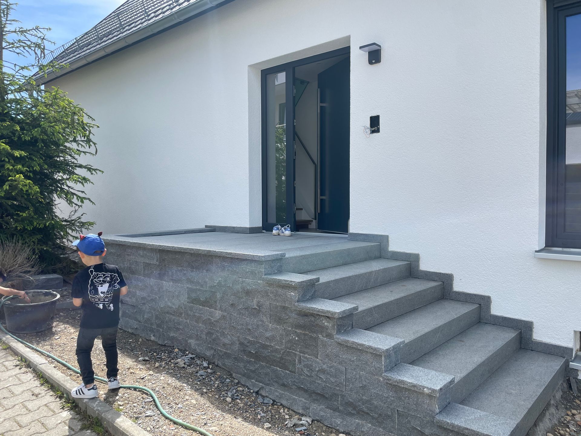 Moderne Außentreppe aus Betonblöcken vor dem Hauseingang.