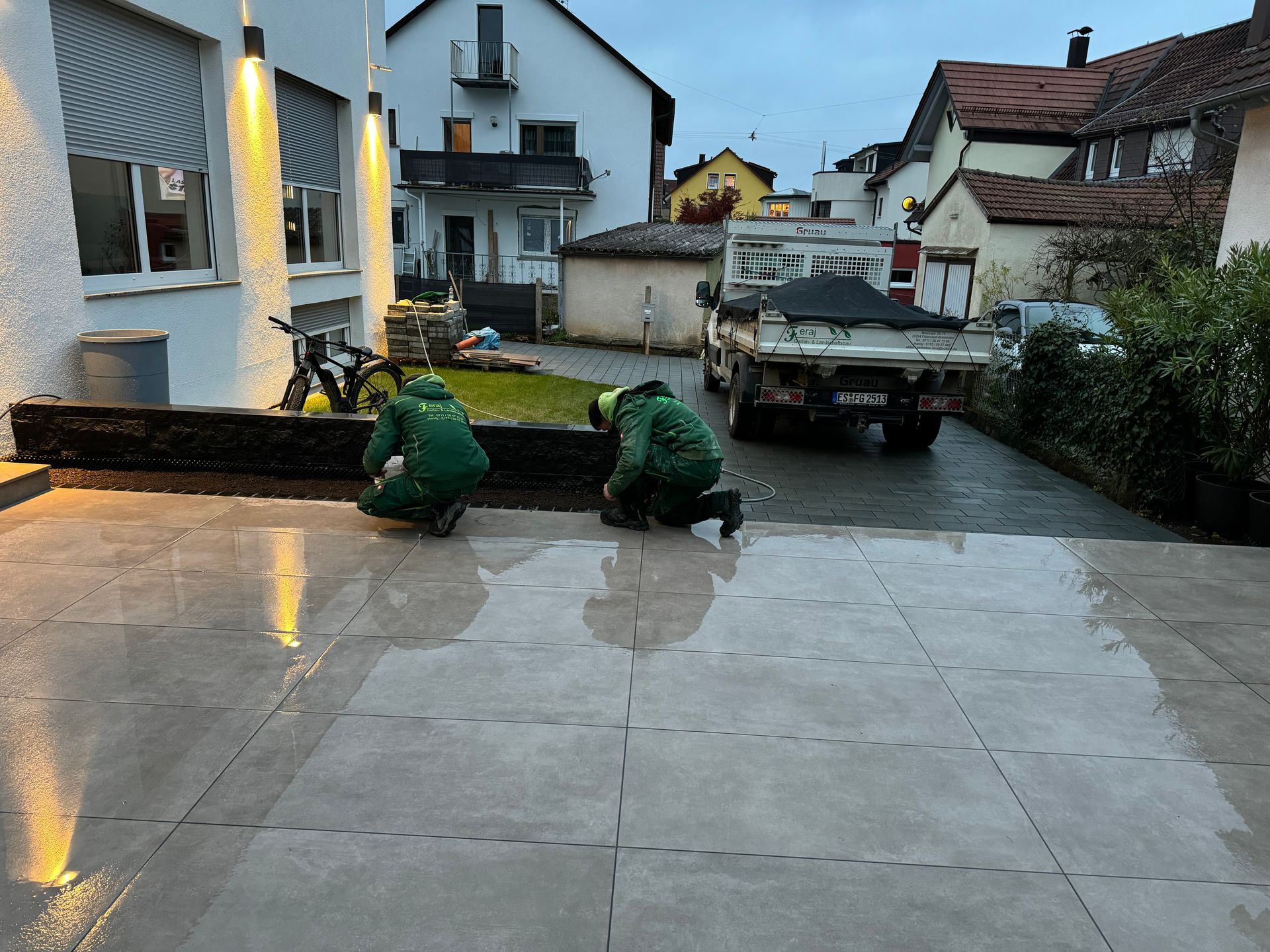 Gartenbau-Team bei Reinigungsarbeiten auf einer Einfahrt.