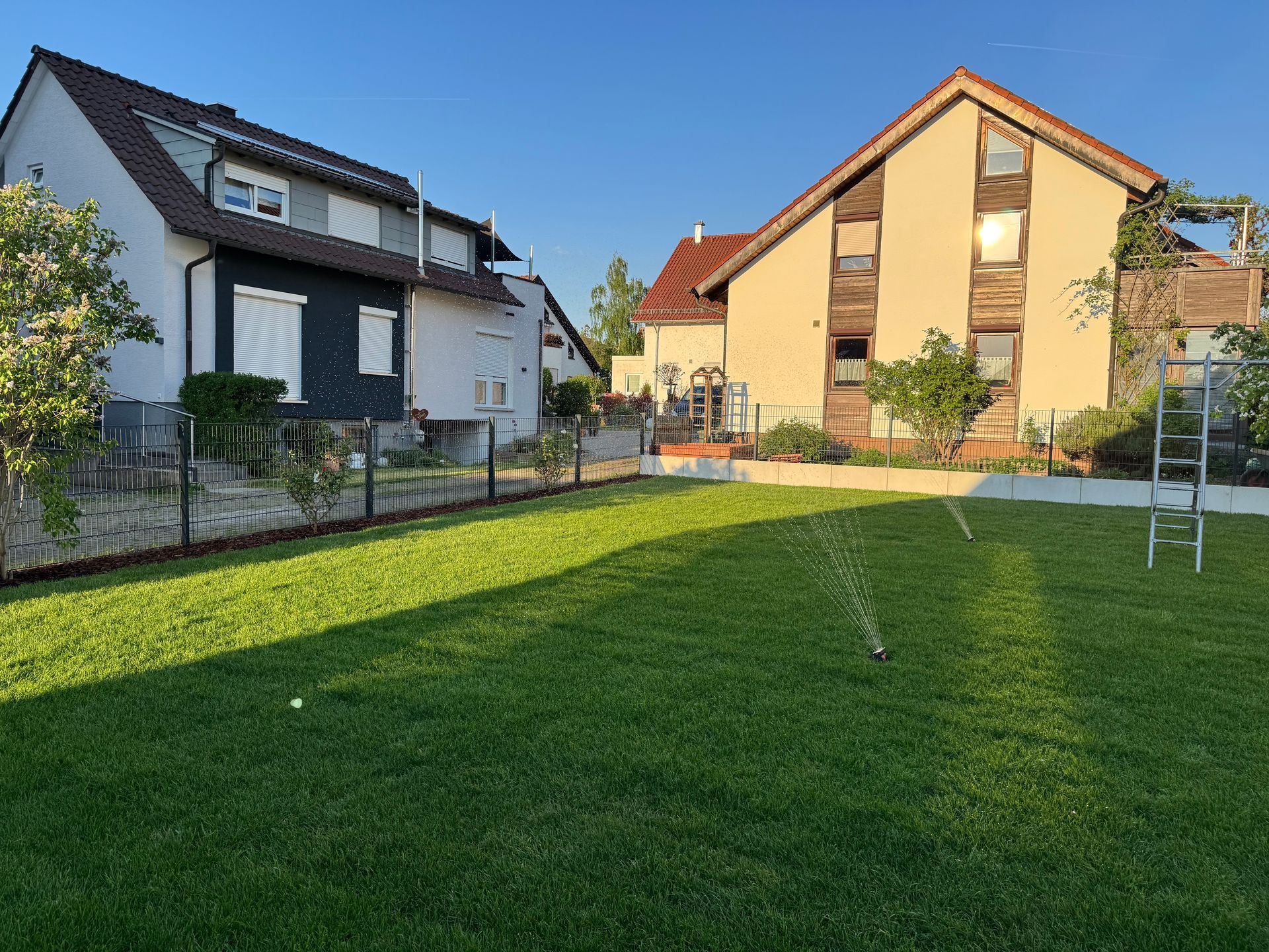 Großzügige Rasenfläche vor modernen Einfamilienhäusern.