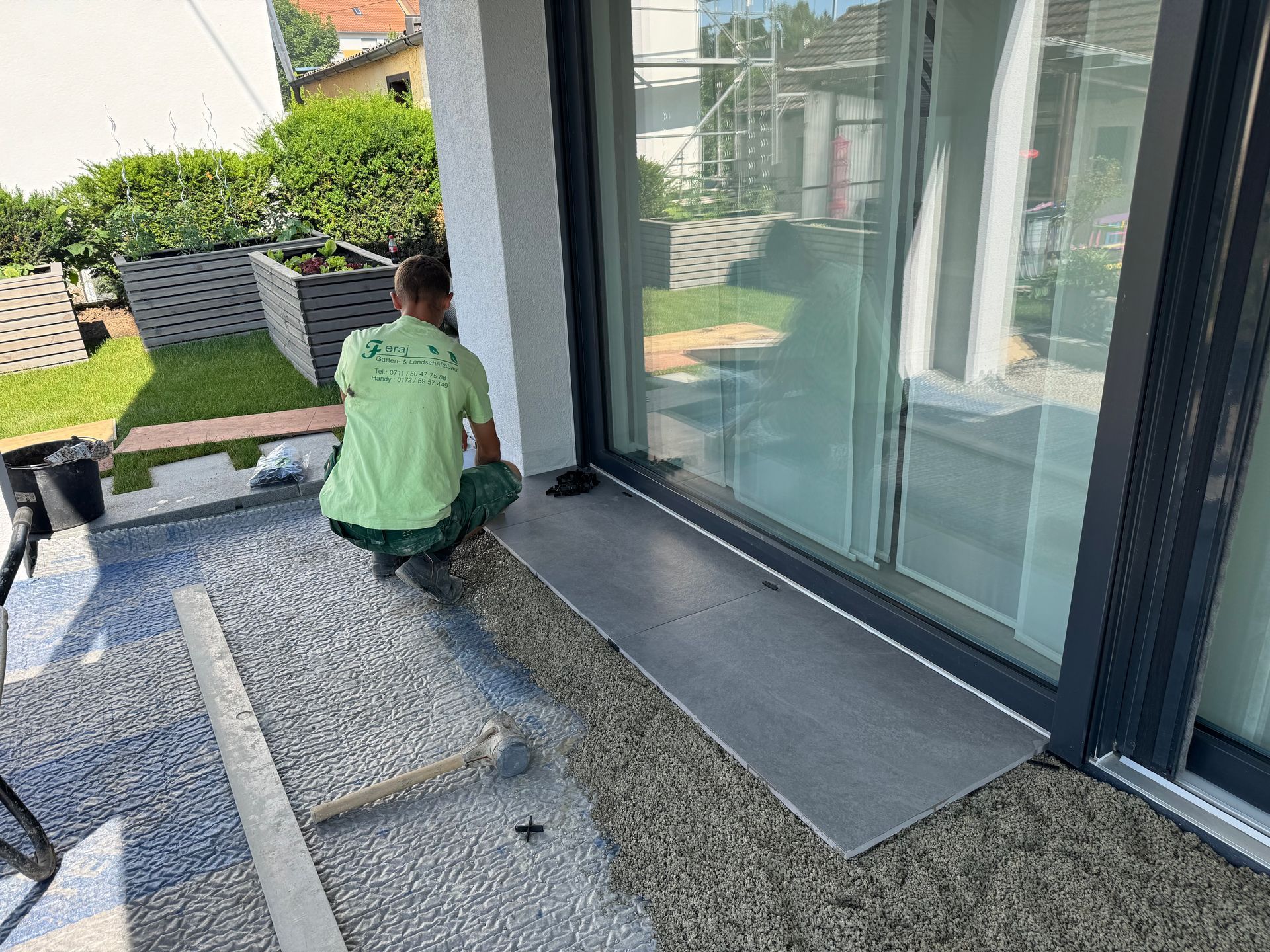 Gartenbauer verlegt Steine auf einer modernen Terrasse.