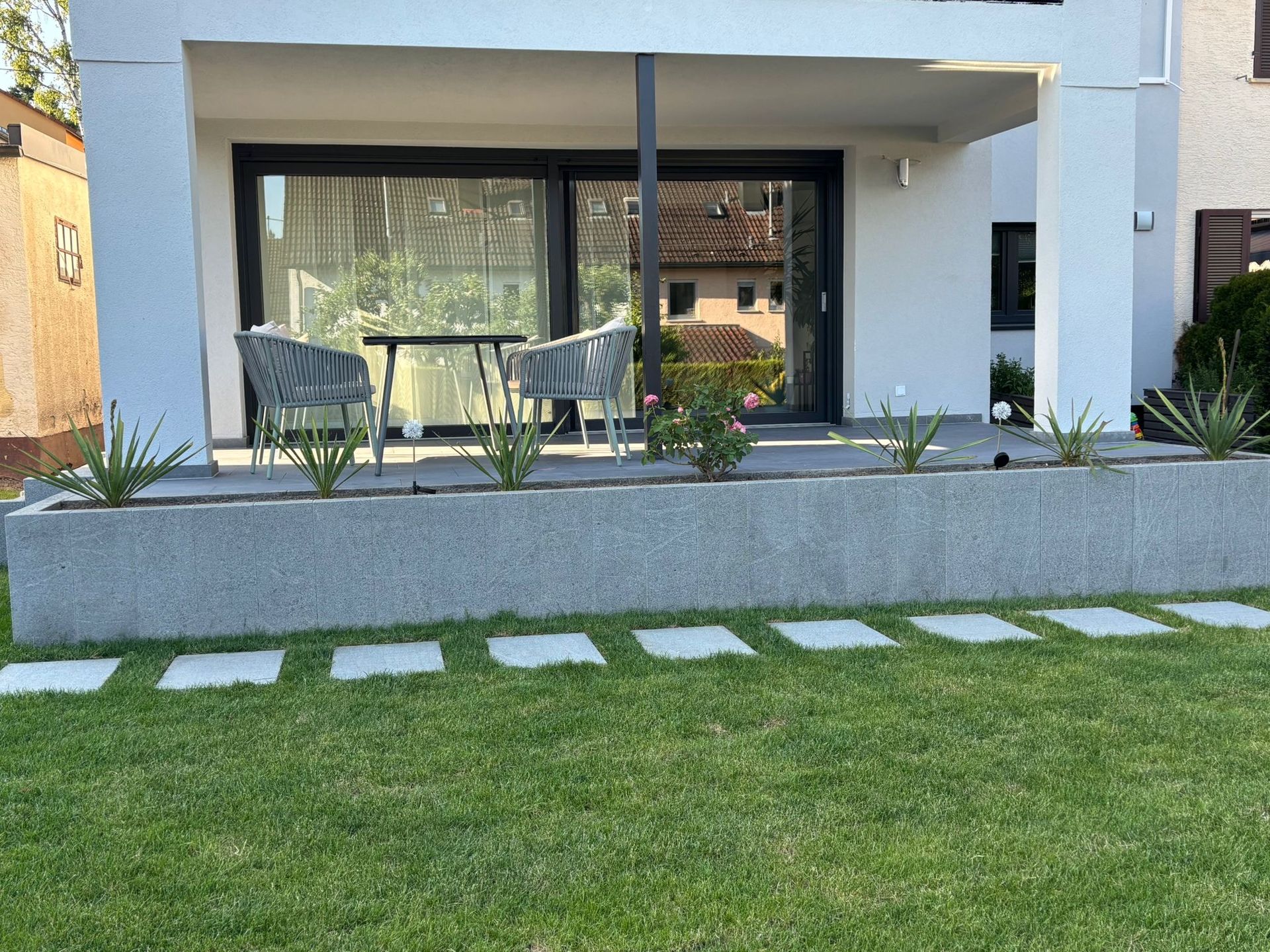 Terrasse mit Sitzgruppe, Granit-Einfassung und Trittsteinen.