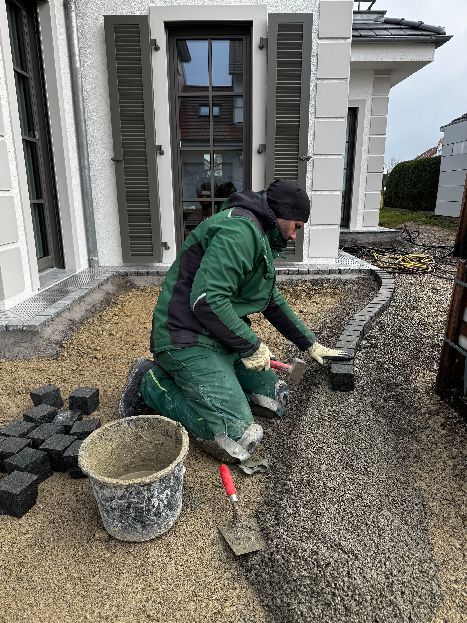 Handwerker bei Fassadenarbeiten an einem weißen Haus.