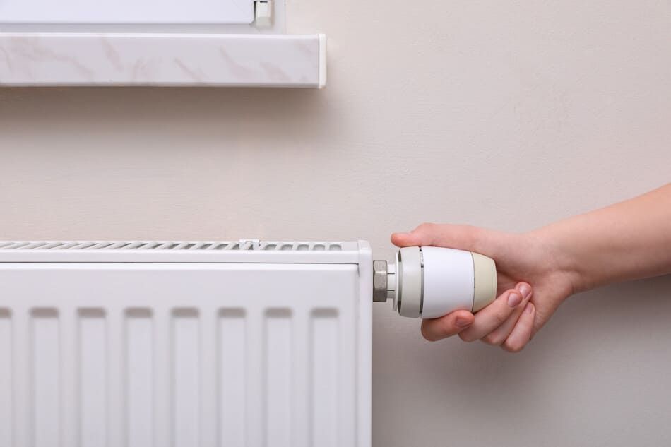 Una persona está ajustando el termostato de un radiador.