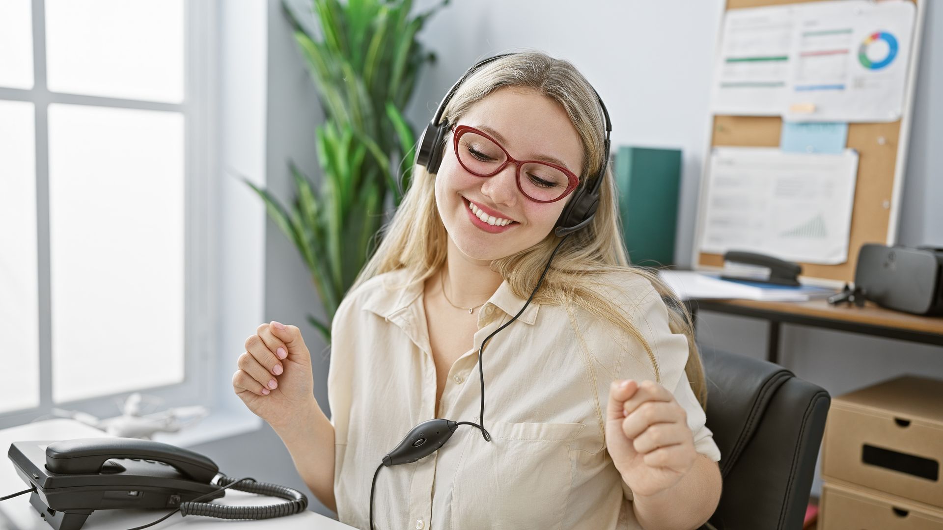Une femme bonde souriant face à son bureau.