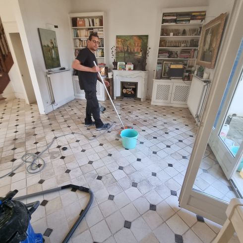 Un homme qui nettoie un sol dans une maison.