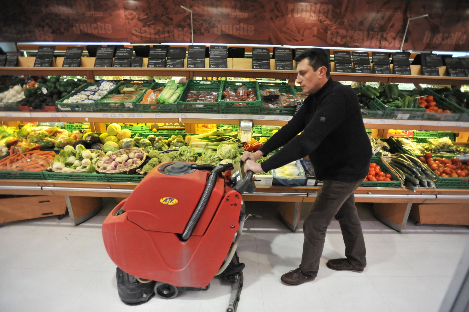 Un homme qui nettoie le sol d'un supermarché.