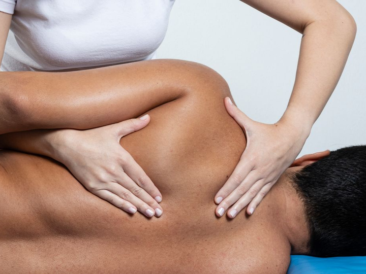Une personne reçoit un massage des épaules de la part d'une personne portant une chemise blanche.