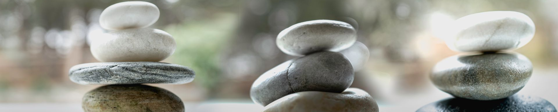 Trois piles de pierres en équilibre devant un fond vert flou.