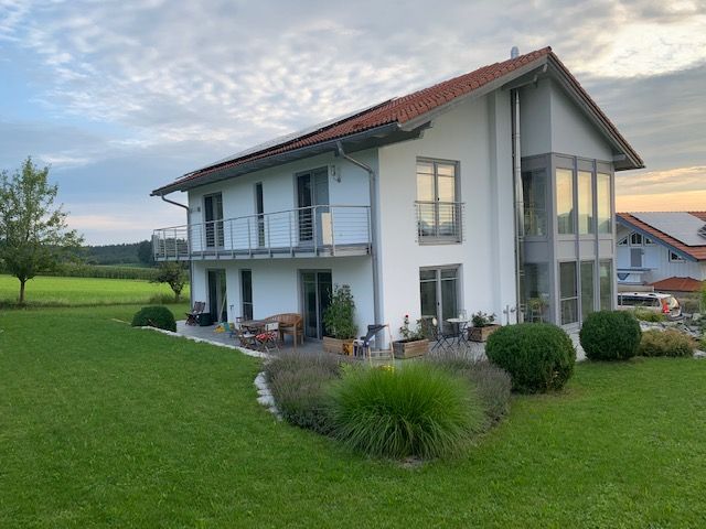 Haus mit weißer Fassade auf grüner Wiese