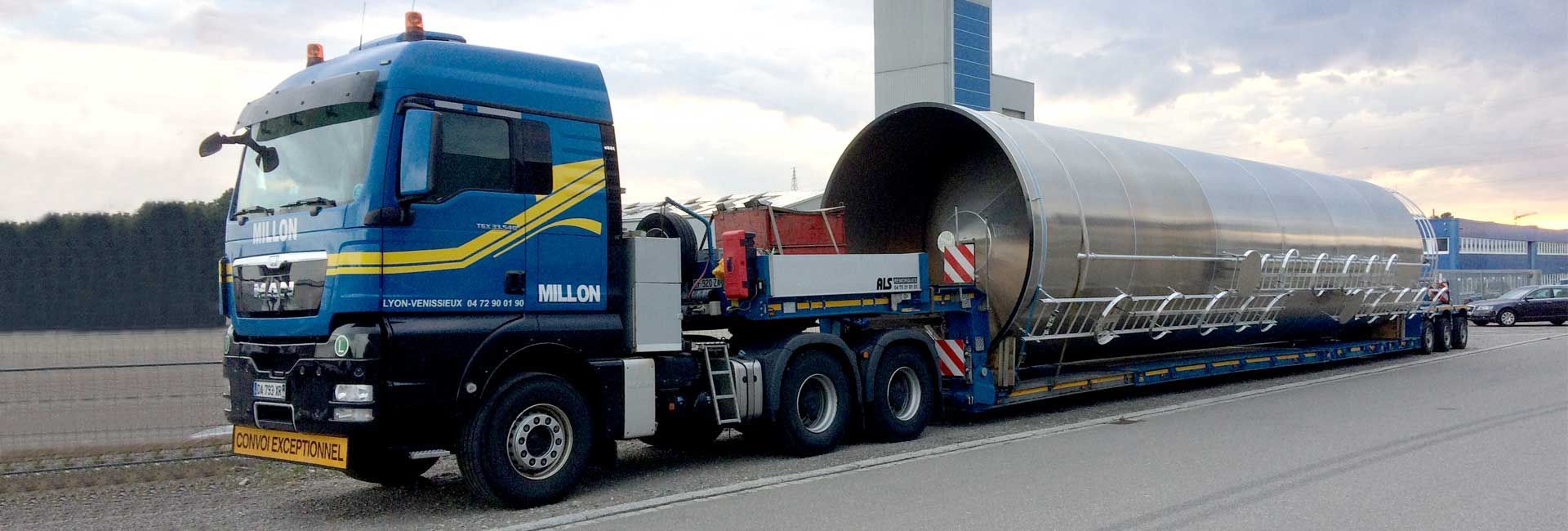 Un semi-remorque MAN bleu stationné sur un parking asphalté, transportant une très grande cuve métallique industrielle cylindrique.