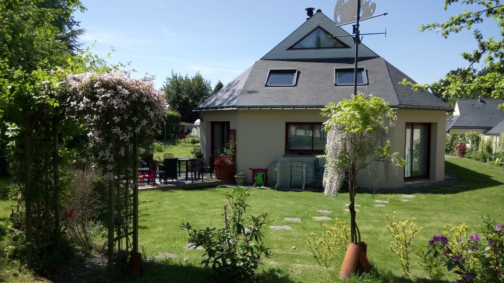 Maison avec un toit très pointu et un jardin autour