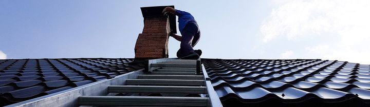 Un ramoneur à côté d’une cheminée sur le toit d’une maison