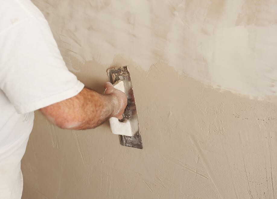 Un hombre está enyesando una pared con una paleta.