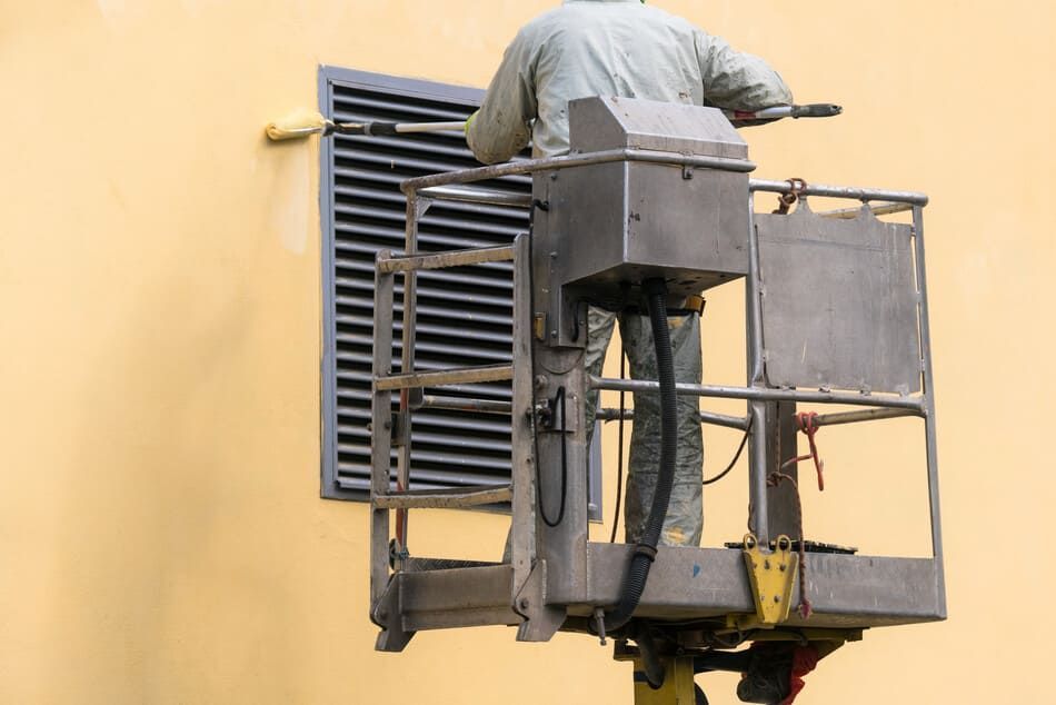 Un hombre está pintando una ventana en el costado de un edificio.