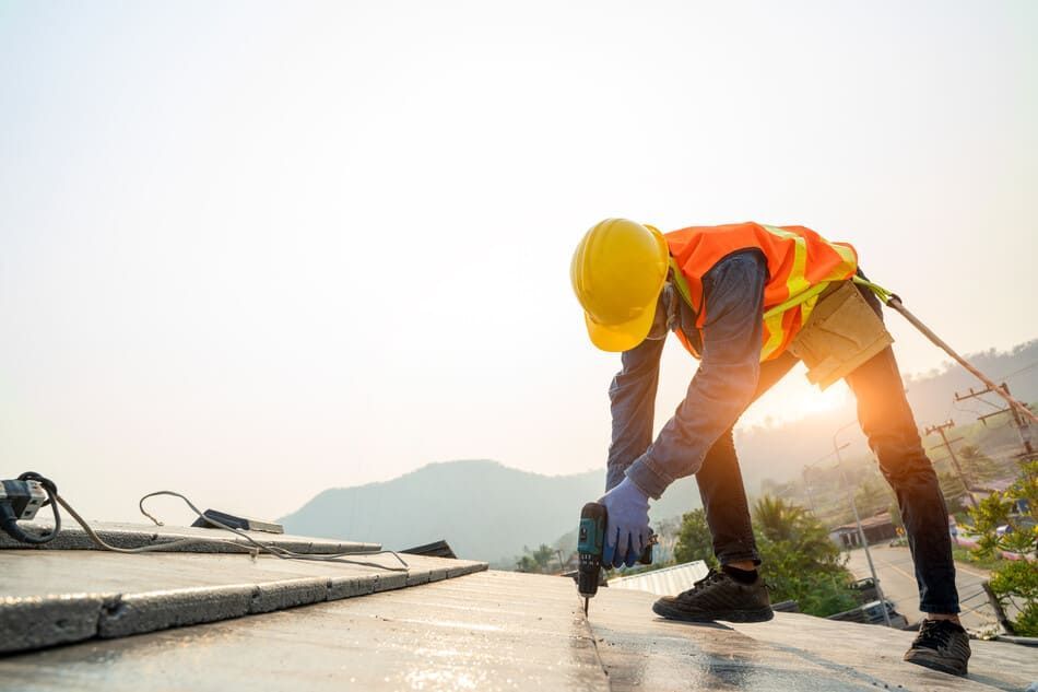 Un trabajador de la construcción está trabajando en un tejado con un taladro.