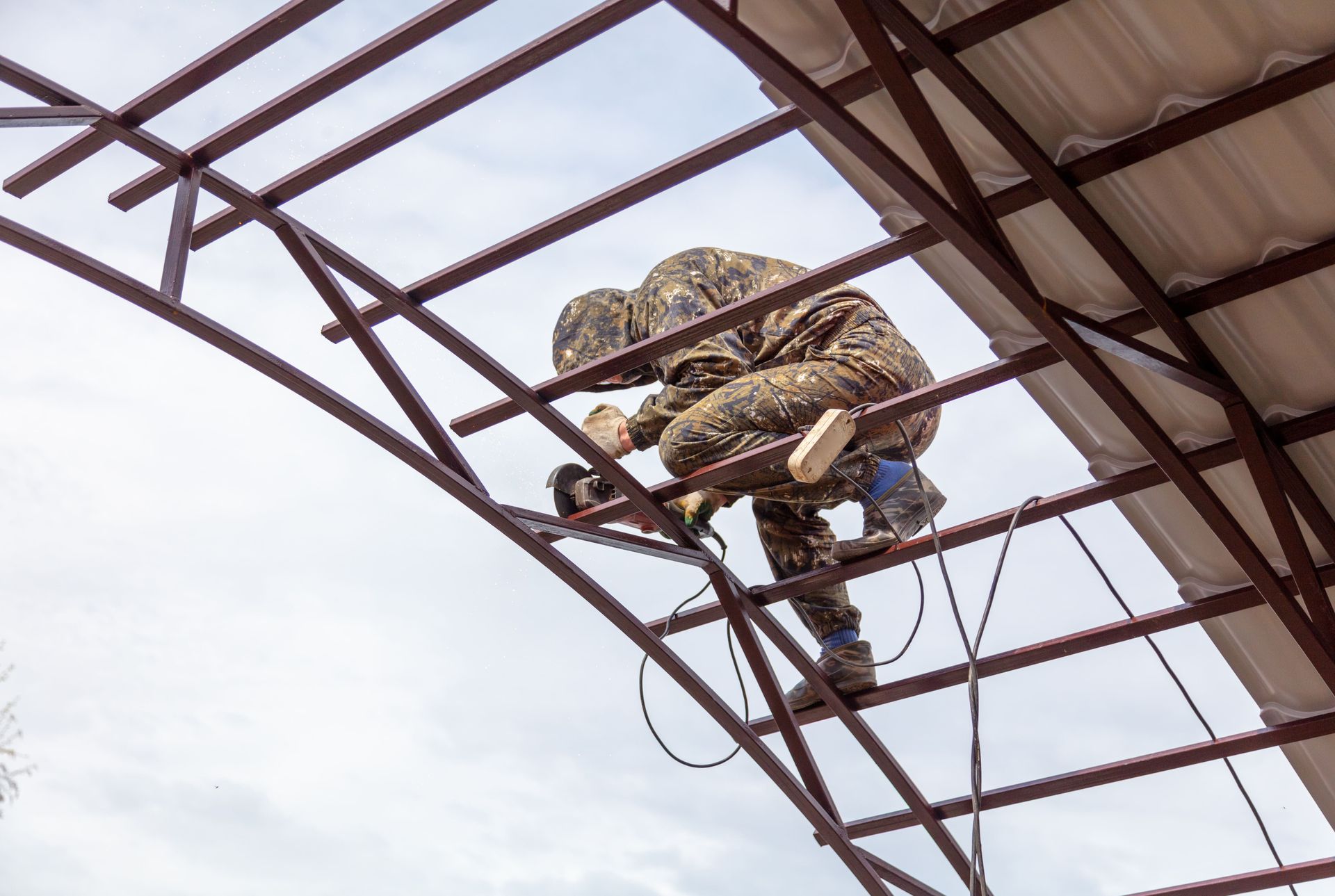 Un hombre está trabajando en una estructura de metal en la parte superior de un edificio.