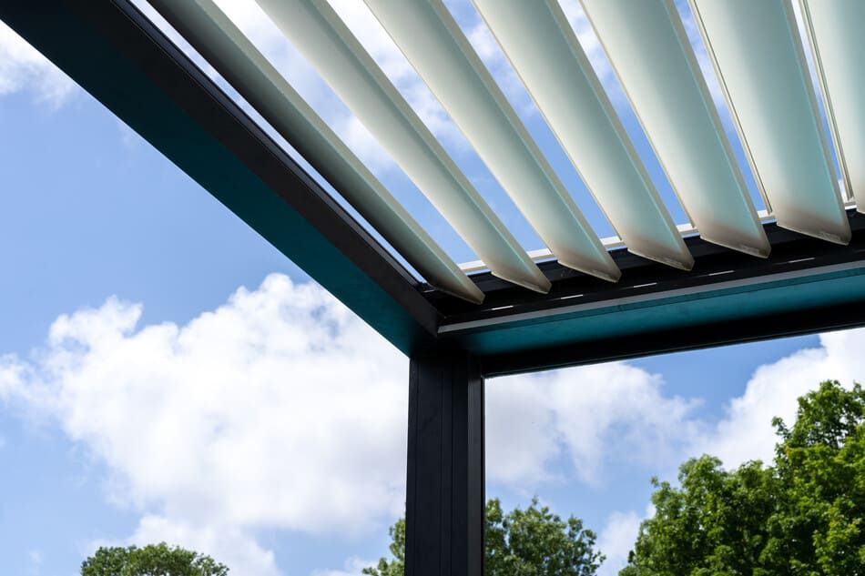 Una pérgola con un cielo azul y árboles al fondo.