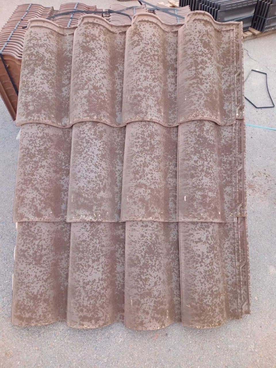 Una pila de baldosas marrones colocadas encima de una superficie de hormigón.