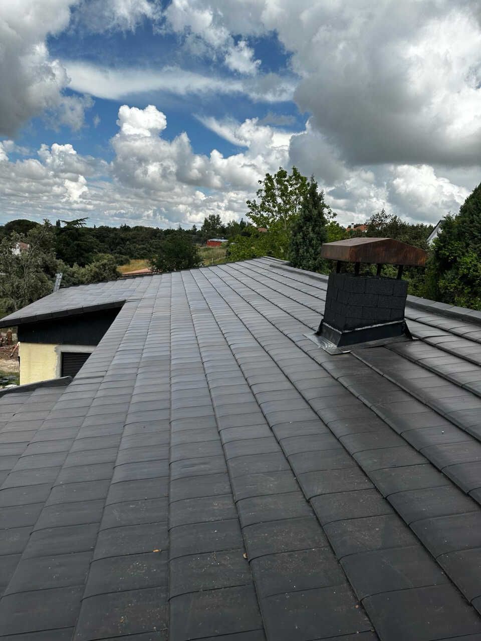 Un techo negro con una chimenea encima.