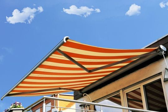 Un toldo de rayas naranjas y amarillas está en un balcón.