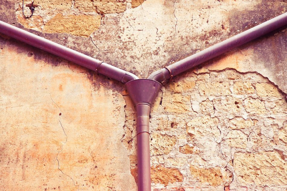 Una tubería violeta está conectada a una pared de ladrillos.
