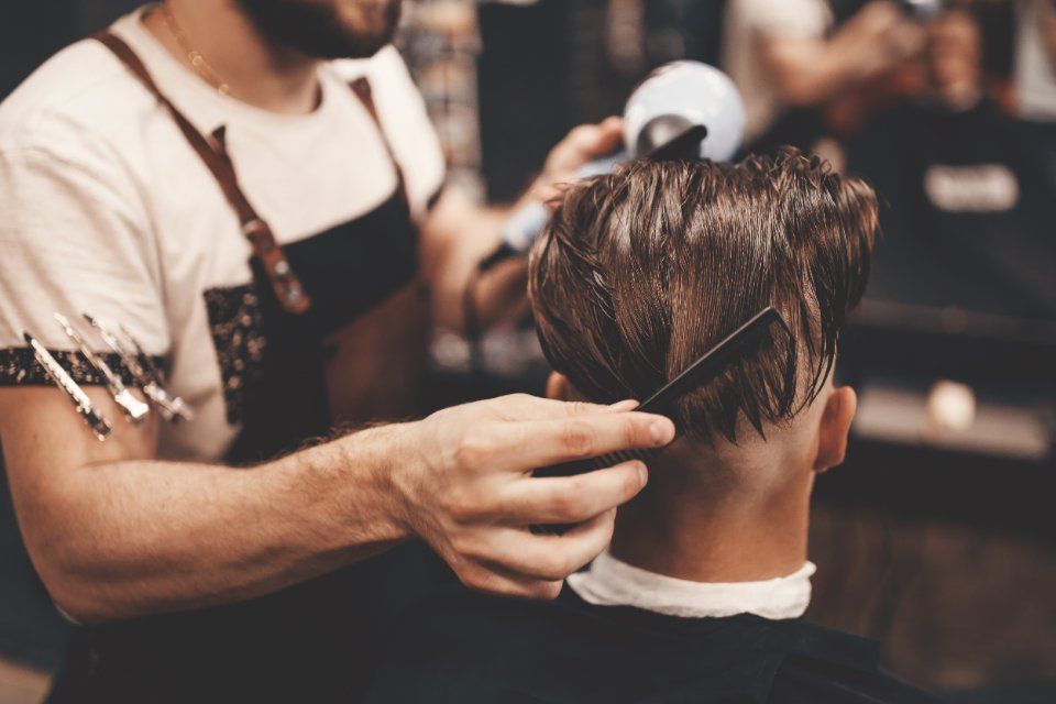 Ein junger Mann bekommt vom Friseur im Salon Black & White in Ansbach einen neuen Haarschnitt.