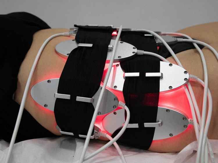 Una mujer está acostada en una cama con un dispositivo en la espalda.